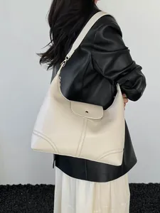 Minimalist beige tote bag in smooth leather finish shown on a model with a black leather jacket