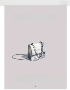Dettaglio mini borsa a tracolla con texture marmo blu, ciondolo di perle e catena metallica