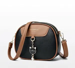 Zijaanzicht van de zwarte crossbodytas met bruine riemen en een kattenhanger