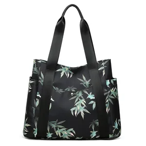 Black tote bag with green bamboo print featuring metal buckle pocket and shoulder straps