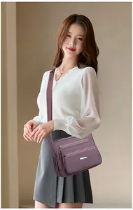 Detail einer dunkelvioletten Nylon-Umhängetasche mit Reißverschlüssen und Tragegurt