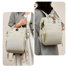 Mochila para pañales versátil mostrada de mano y espalda en un estudio suave