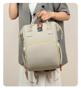 Detalle de la bolsa de pañales multifuncional beige con asas dobles y cremalleras duraderas