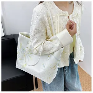 Chic tote bag featuring blue and gold bamboo leaves pattern worn by a model
