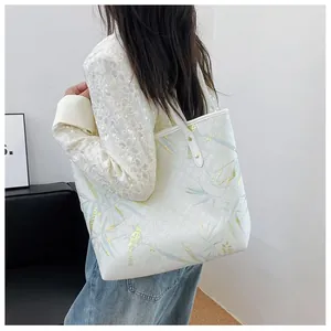 Detailed close-up of white tote bag with gold bird pattern and vintage embossed texture