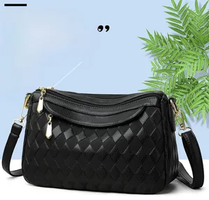 Detail of black crossbody bag with triple zippers and golden hardware on blue background
