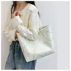 Detail of elegant bamboo and bird embroidery on cream tote bag with chic Chinese style