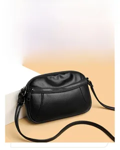 Detail of black pebbled leather crossbody bag with adjustable strap and metallic zipper