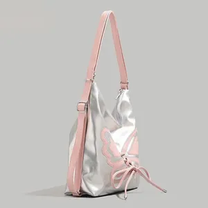 Detail of silver metallic butterfly shoulder bag with pink bows and strap accents