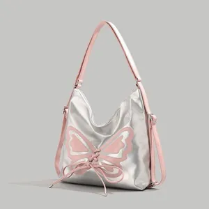 Detail of silver metallic hobo bag featuring pink leather strap and butterfly patch