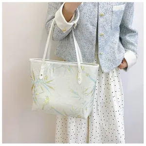 Detail of floral tote bag with blue birds and branches pattern on cream base