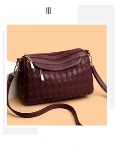 Detail of burgundy crossbody bag featuring triple zipper pockets and lychee grain leather
