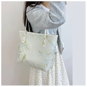Detail view of large tote bag with bamboo leaf print on light blue tweed jacket