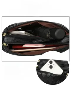 Close-up of black litchi leather bag showing three zipper layers and large inner capacity