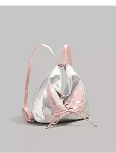 Detail of silver metallic backpack featuring pink butterfly wings and ribbon lacing