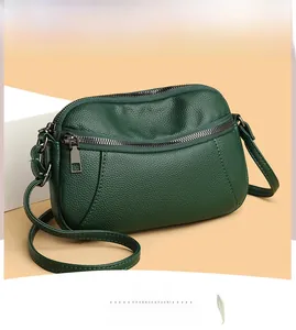 Detail of dark green pebbled leather shoulder bag with gunmetal zippers and hardware