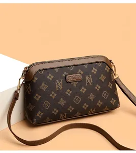 Detail of dark brown vintage floral crossbody bag with gold hardware and smooth zipper