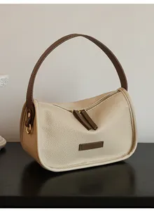 Detail view of lychee-textured beige leather underarm bag with dark brown trim