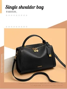 Détail du sac Boston en cuir grainé noir avec logo doré et finitions métalliques dorées