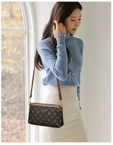Close-up of small crossbody phone bag with vintage floral pattern and gold zipper details
