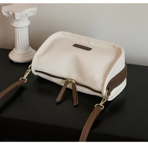 Detail of dual-tone leather bag with lychee texture and premium gold metal zippers