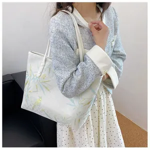 Detail of a white tote bag featuring blue bamboo leaves and bird patterns in Chinese style