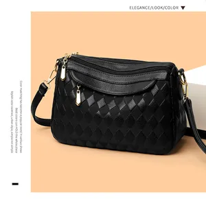 Detail of black crossbody bag with lychee and diamond pattern and gold zippers