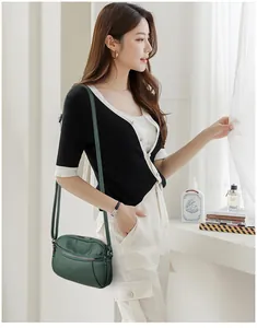 Detail of dark green pebbled leather crossbody bag with multiple zippers and adjustable strap