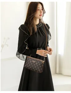 Close-up of brown crossbody bag with classic monogram pattern and premium zipper detail