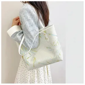 Detail of Chinese style tote bag with bird and bamboo patterns worn by a model