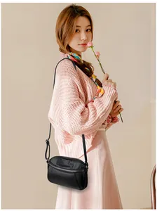 Close-up of black pebble leather crossbody bag with silver zipper and slim strap