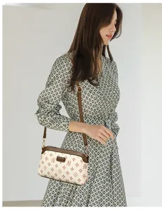 Close-up of vintage monogram crossbody bag with adjustable strap worn on floral dress