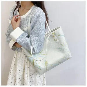 Detailed close-up of a white leather tote bag with elegant blue kingfisher and bamboo prints