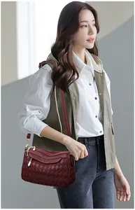 Detail of burgundy quilted crossbody bag showing gold zippers and textured pattern