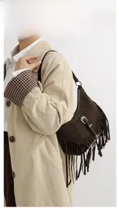 Détail du sac bandoulière en daim marron foncé avec franges bohèmes et boucle gravée