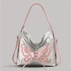 Silver metallic butterfly shoulder bag with pink bow accents and long strap