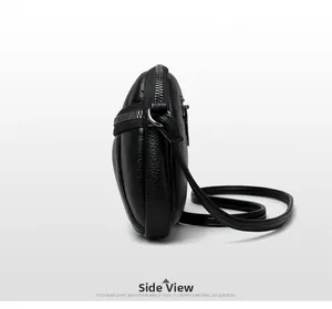 Side view of black pebble leather crossbody round bag with silver zipper and fine strap