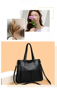 Detail of black pebbled leather tote bag with adjustable strap and stitched texture