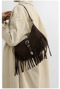 Détail d'un sac bandoulière vintage en daim marron avec franges et boucle sculptée