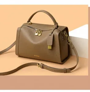Détail du sac Boston en cuir grainé taupe avec des accessoires dorés et texte fashion