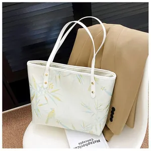 Elegant white tote bag with bamboo and bird pattern on a chair in a professional setting