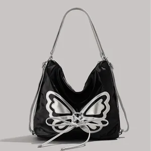Y2K style black glossy shoulder bag featuring a large silver butterfly and bow detail