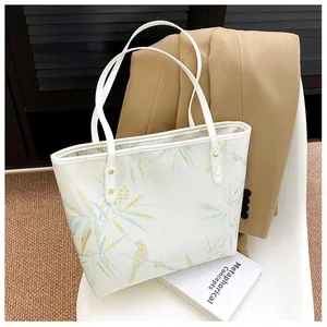 Detail of white tote bag featuring bamboo leaf prints and elegant golden rivets
