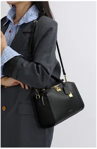 Detailansicht der schwarzen Handtasche mit Litschi-Muster und goldenen Metallreißverschlüssen