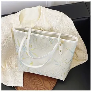 Close-up of elegant bamboo embroidery and golden rivets on beige tote bag