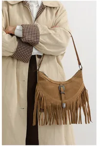Gros plan d'un sac bandoulière en daim marron avec franges rétro et boucle en métal