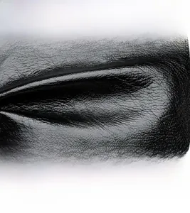 Detail of black lychee grain leather backpack featuring a silver kangaroo logo emblem