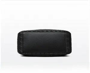 Detailed macro view of black lychee leather handbag bottom with diamond pattern embossing