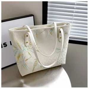 Detailed close-up of large tote bag with blue bamboo leaves and golden bird prints