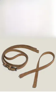Détail de la bandoulière en daim marron avec boucle en métal argenté et couture précise